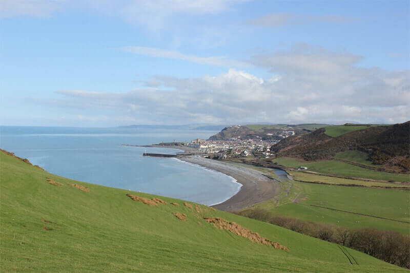 Aberystwyth Bay by Julian Nyča, CC BY-SA 3.0 <https://creativecommons.org/licenses/by-sa/3.0></noscript>, via Wikimedia Commons” title=”Aberystwyth Bay by Julian Nyča, CC BY-SA 3.0, via Wikimedia Commons” align=”left”></a>Elephants bathe in the sea at Aberystwyth watched idly by locals who are getting used to the sight. The circus was in town again so why should this be unusual? This was rapidly becoming a popular tourist destination, the Bandstand on the sea front was always busy on a Sunday afternoon, and here was the longest Pier in the west of Britain. It is, of course, the later part of the 19th century, although even now you can be surprised to see the odd elephant or camel in the field near the railway crossing when the circus is in town. In nearby Tregaron, just a bus ride from Aberystwyth, an elephant died of lead poisoning in 1848 and is buried behind the Talbot Hotel. </p>
<p>The funicular railway was opened in 1896, is the 2nd longest in the UK, and is a less-strenuous way to reach the camera obscura on the top of Constitution Hill. The darkness as you enter the small building housing the camera is strangely comforting, the large disc of light drawing you in and sounds around you seem somehow muffled as you gaze at the distorted image of the coastline below.</p>
<p><img decoding=