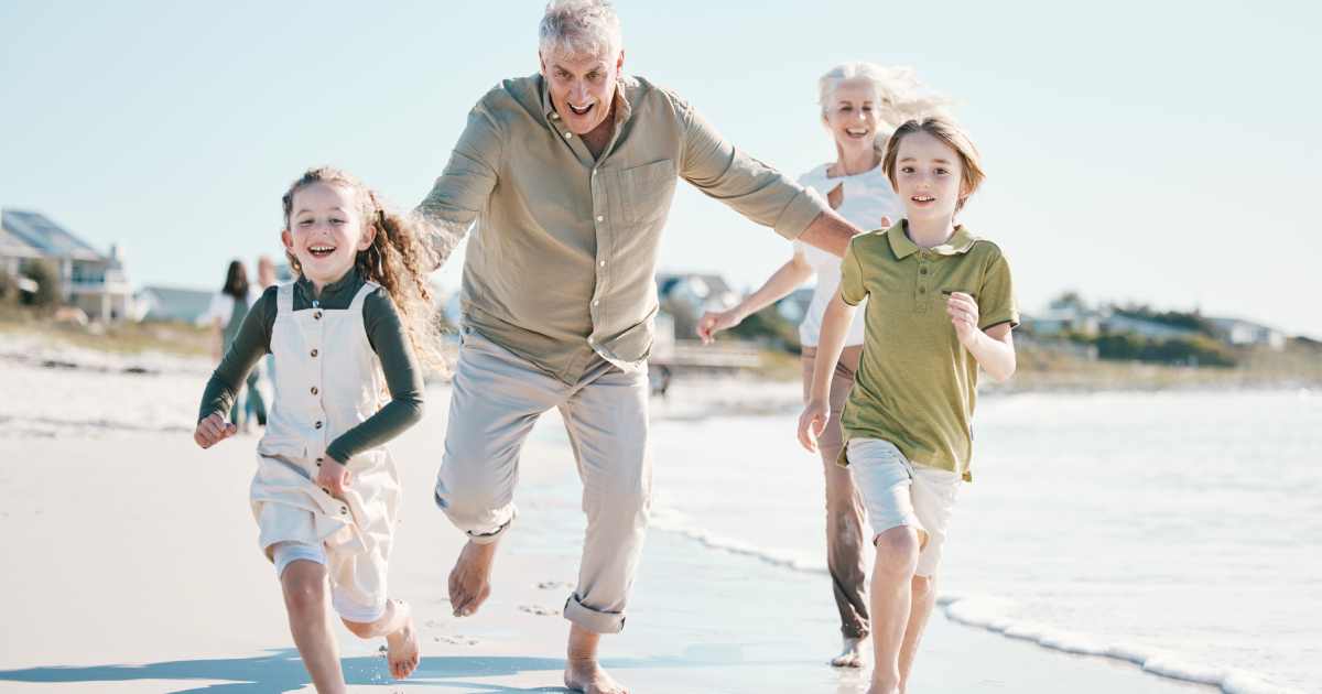 Running, happy and grandparents with children on beach for energy, freedom and summer vacation. Lov | Holidays with Grandchildren