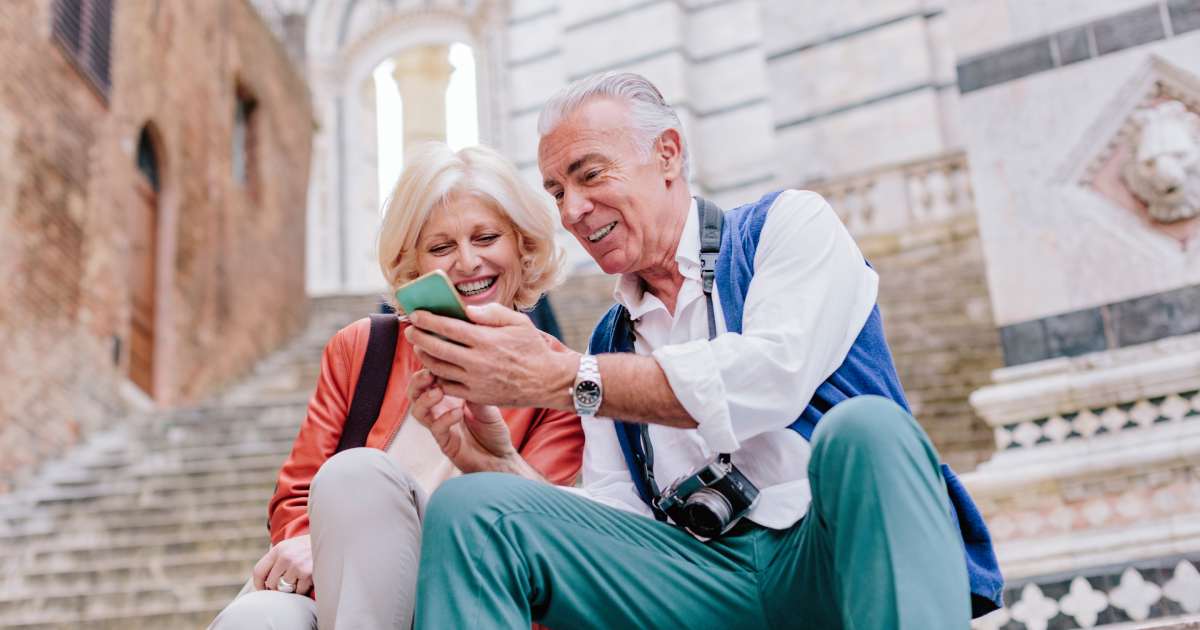 Tourist couple looking at smartphone on Siena cathedral stairway, Tuscany, Italy | Global Retirement Retreat