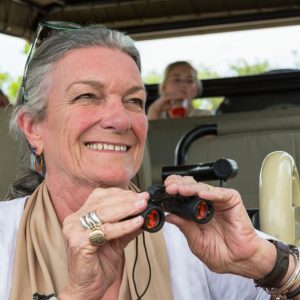 A family in a safari jeep in a wildlife reserve, a seniorwoman with binoculars. | Adventurous Safari