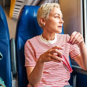 Blonde woman tourist, female traveler, travel blogger traveling looking out the window while sitting in the train. Travel concept | Rail Holidays for Singles