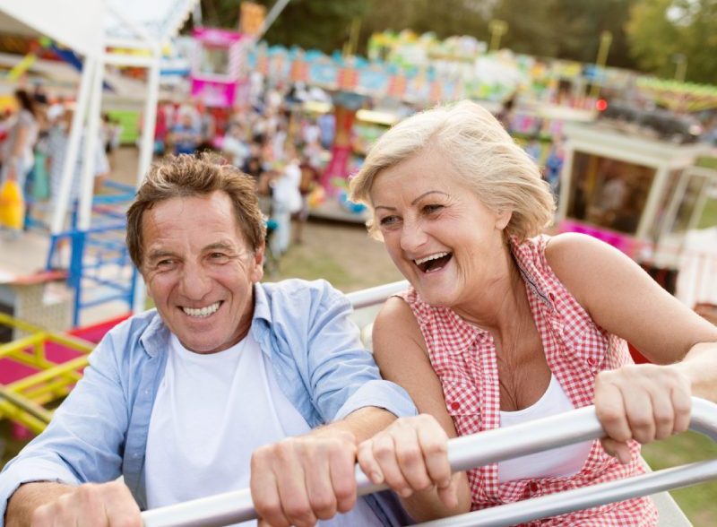Senior couple having fun on a ride in amusement park. Summer vacation. | Holidays to california for couples & families